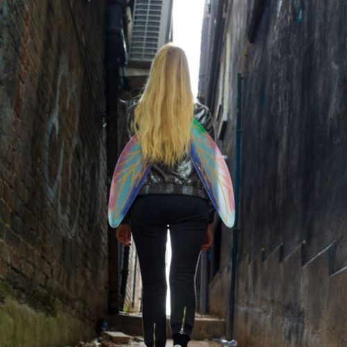 Nicola with fairy wings on in an alleyway