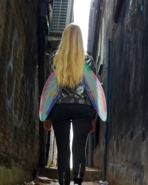 Nicola with fairy wings on in an alleyway